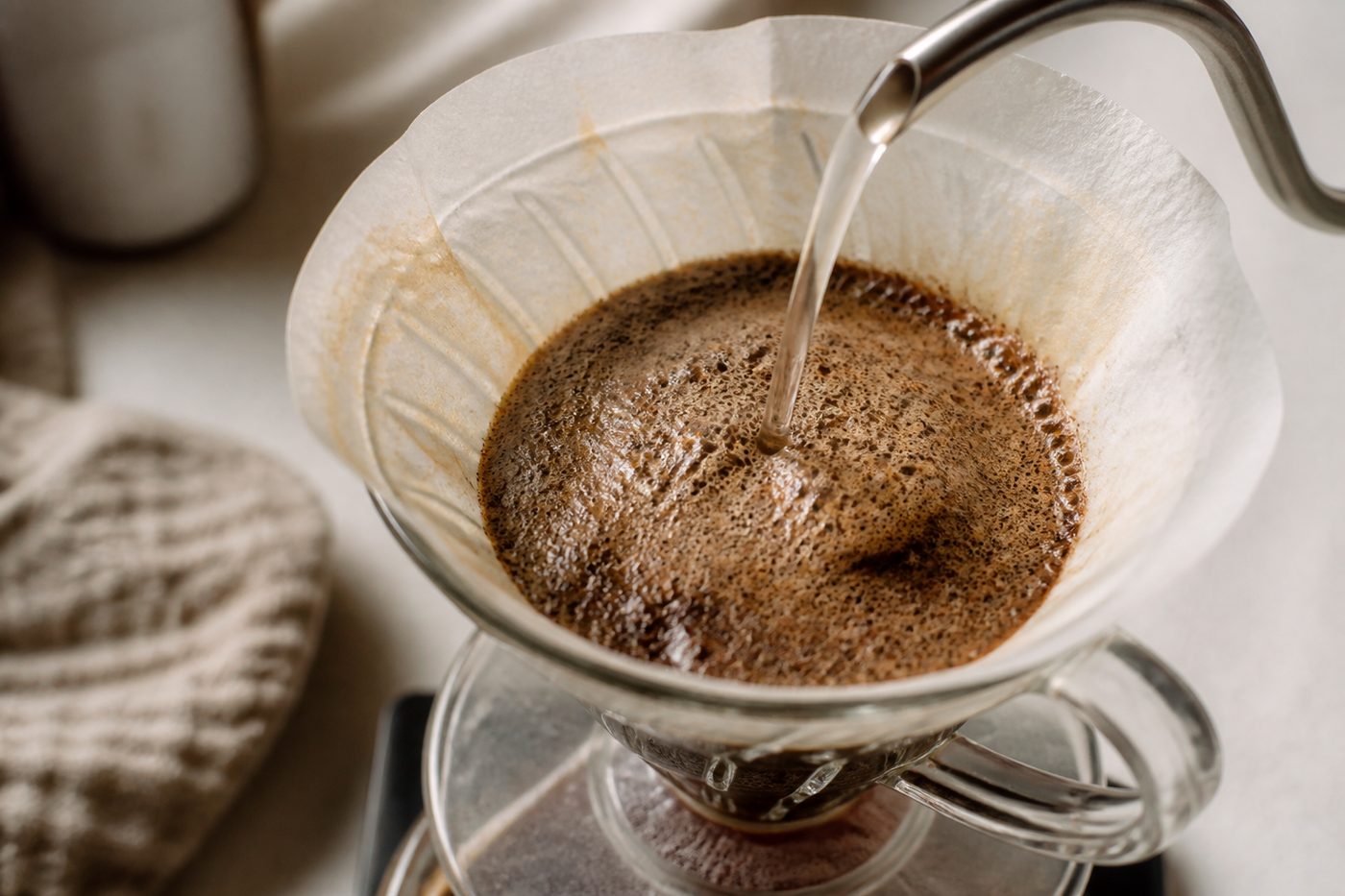 Coffee grounds blooming and releasing bubbles as hot water is poured over them in a pour-over dripper